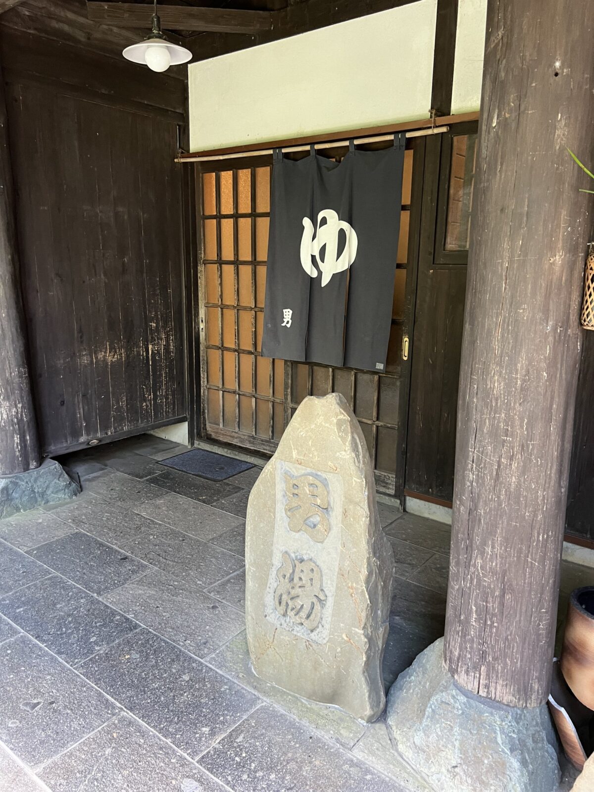 極楽温泉 匠の宿 浴場入口の暖簾と石看板