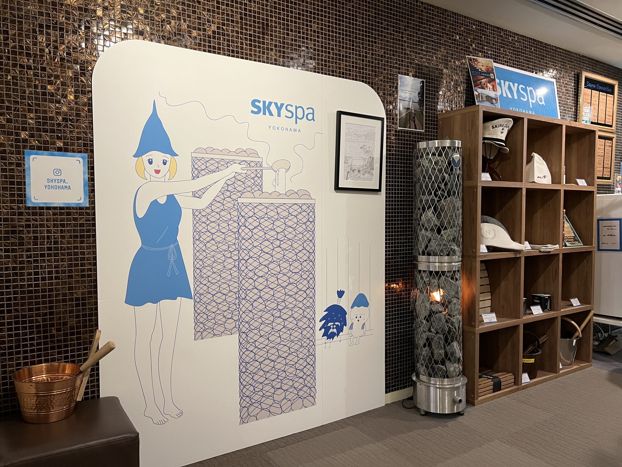 スカイスパYOKOHAMA サウナ室前 ロウリュ説明とサウナハット棚